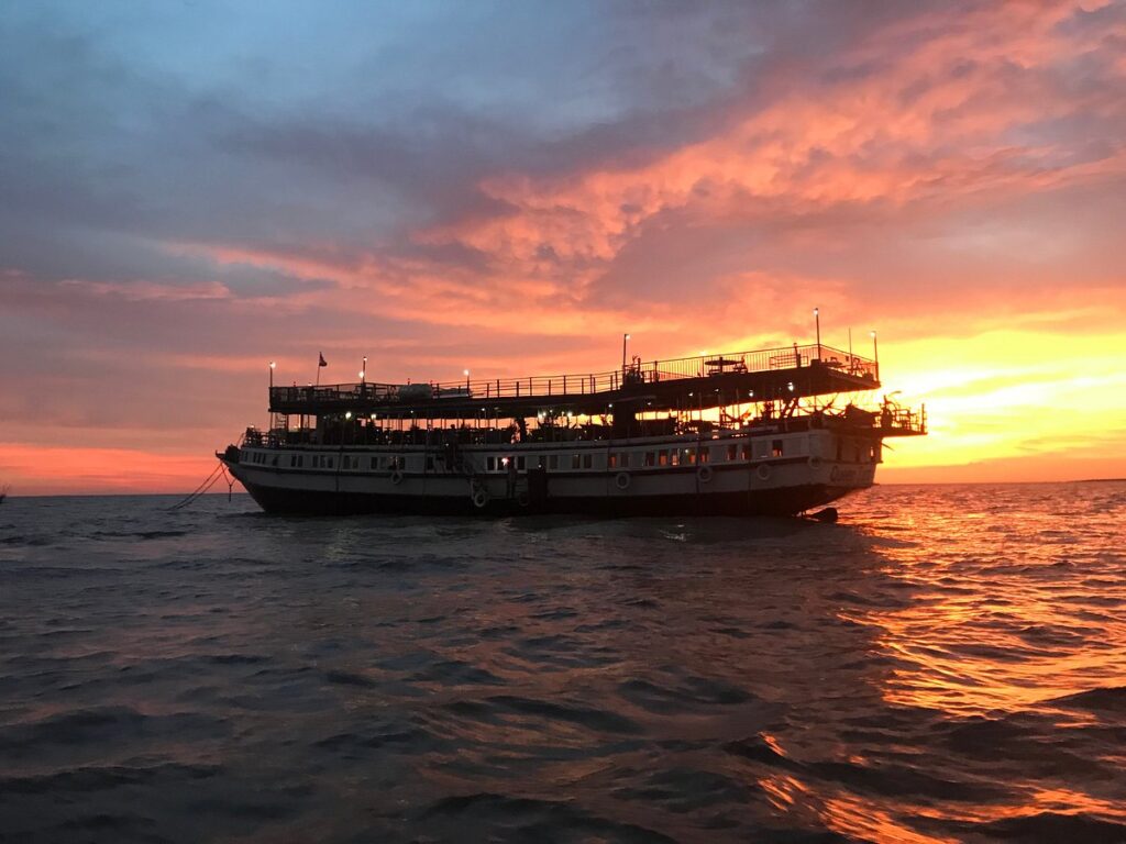 The magnificent Queen Tara riverboat mothership anchored on Tonle Sap Lake, illuminated by a blazing fiery orange and pink tropical sunset sky, as seen in image_6e9add.jpg by Tara Boat.